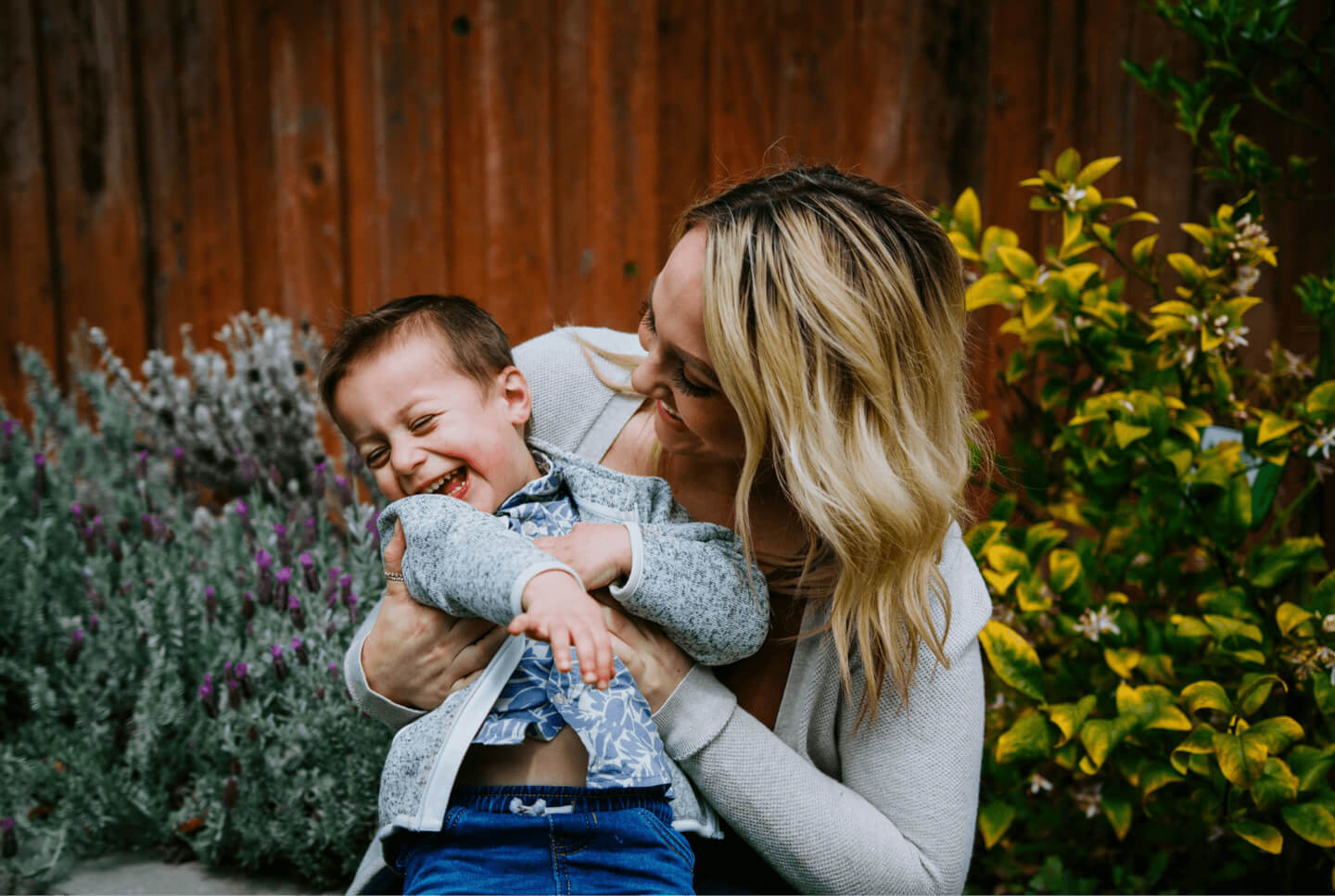 A mother hugging her two young children in a garden