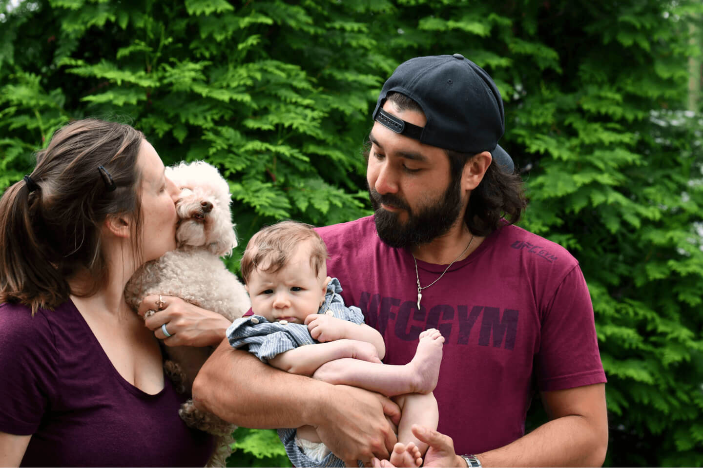 Two young parents outdoors holding their newborn baby