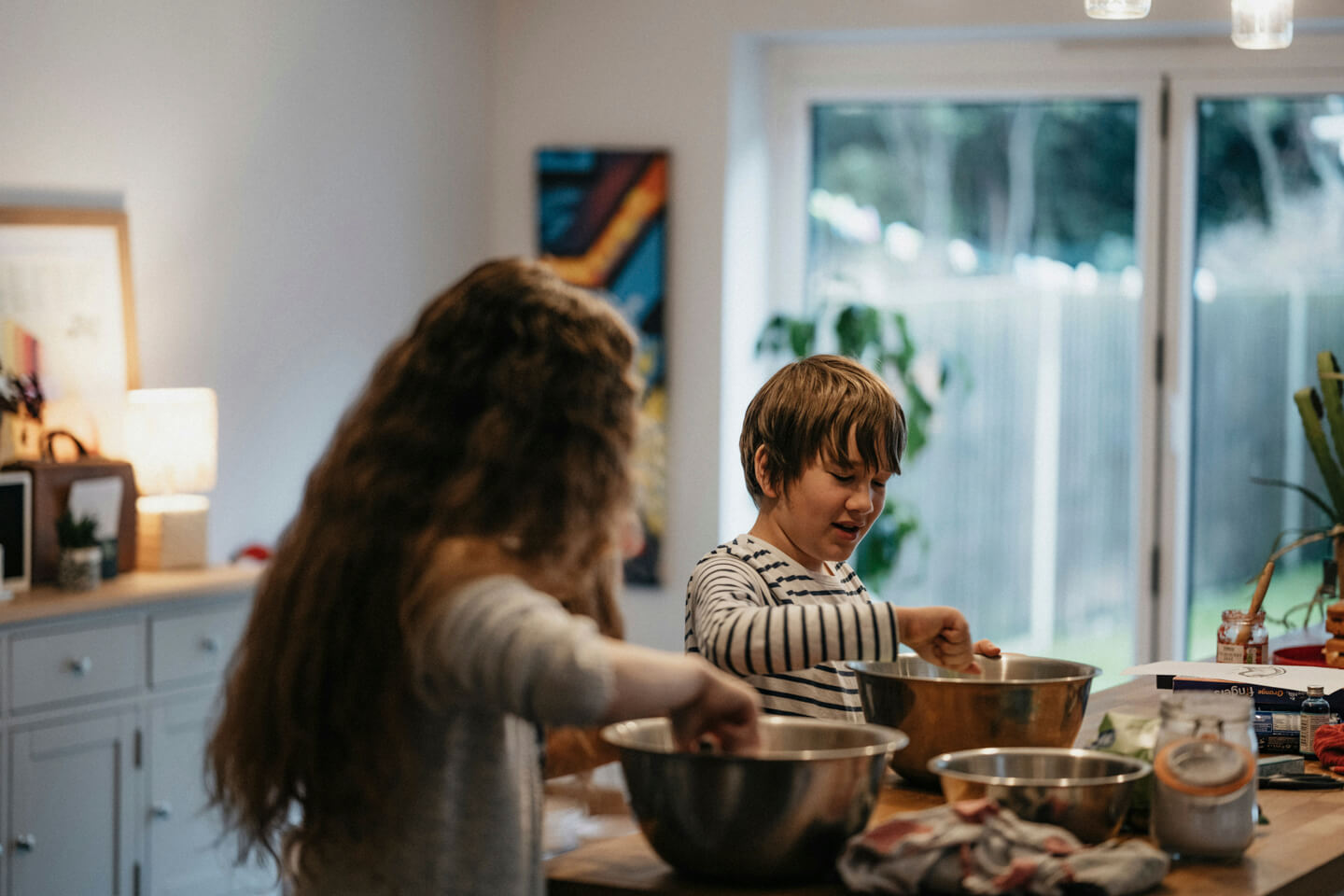 A parent and child preparing food together in a kitchen
