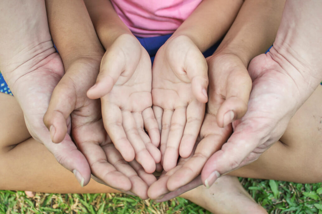 Several pairs of hands, adults and children, cupped together