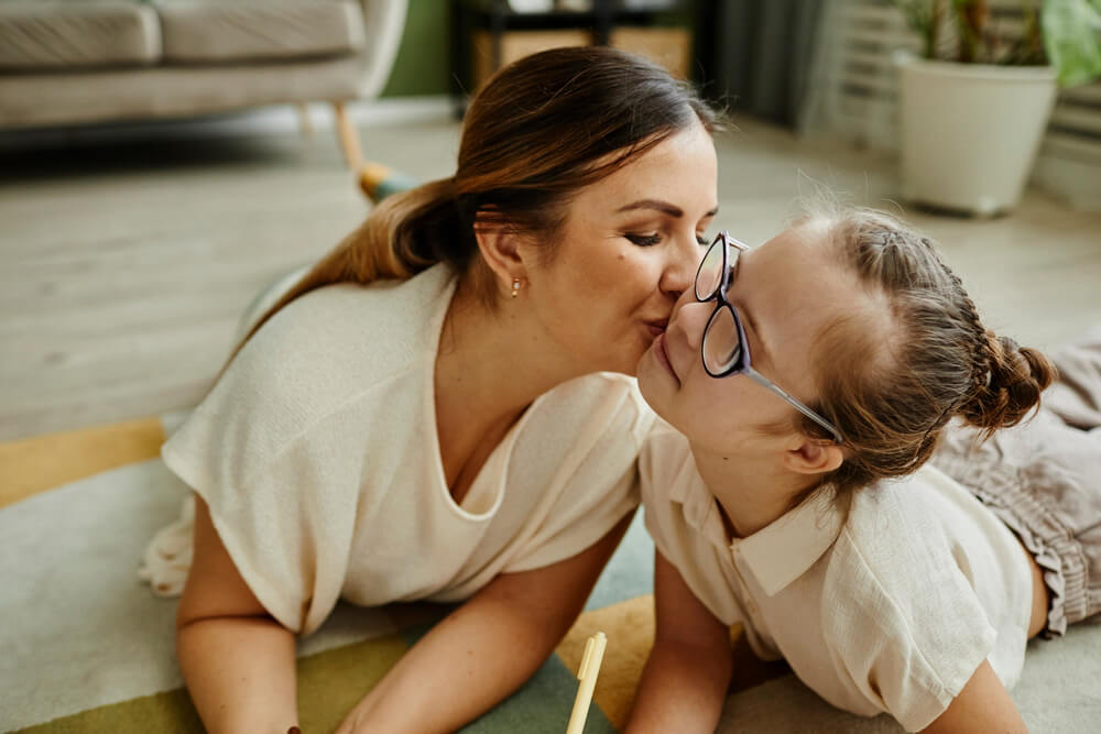 A mother kissing her young daughter on the cheek