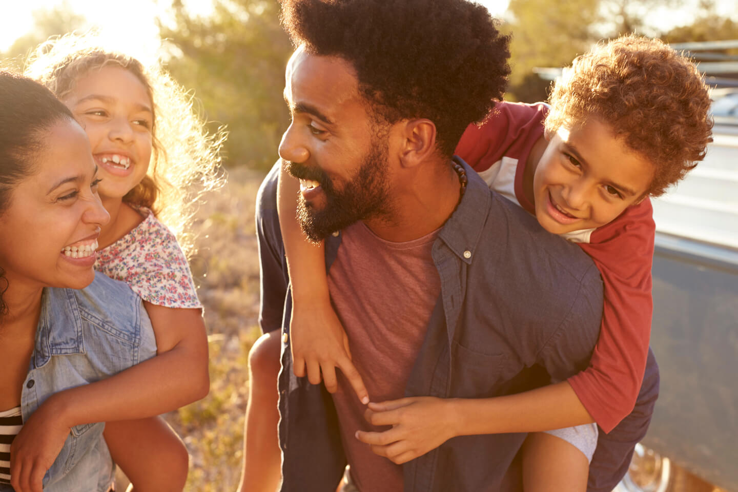 A father laughing outdoors with his two children in evening light